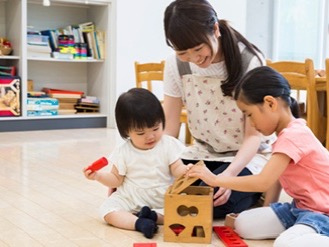 保育室で木のおもちゃを使って遊ぶ子どもたちと保育士