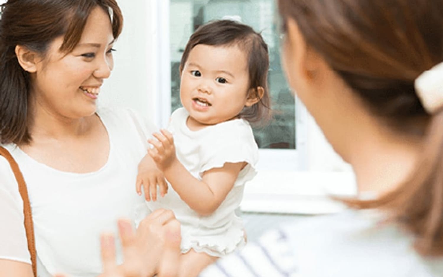 送り迎えの際に保育士と話す保護者と乳児
